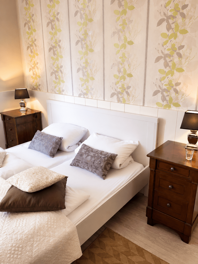 Detailansicht des Zimmers mit Bett, Nachttischen und warmer Beleuchtung